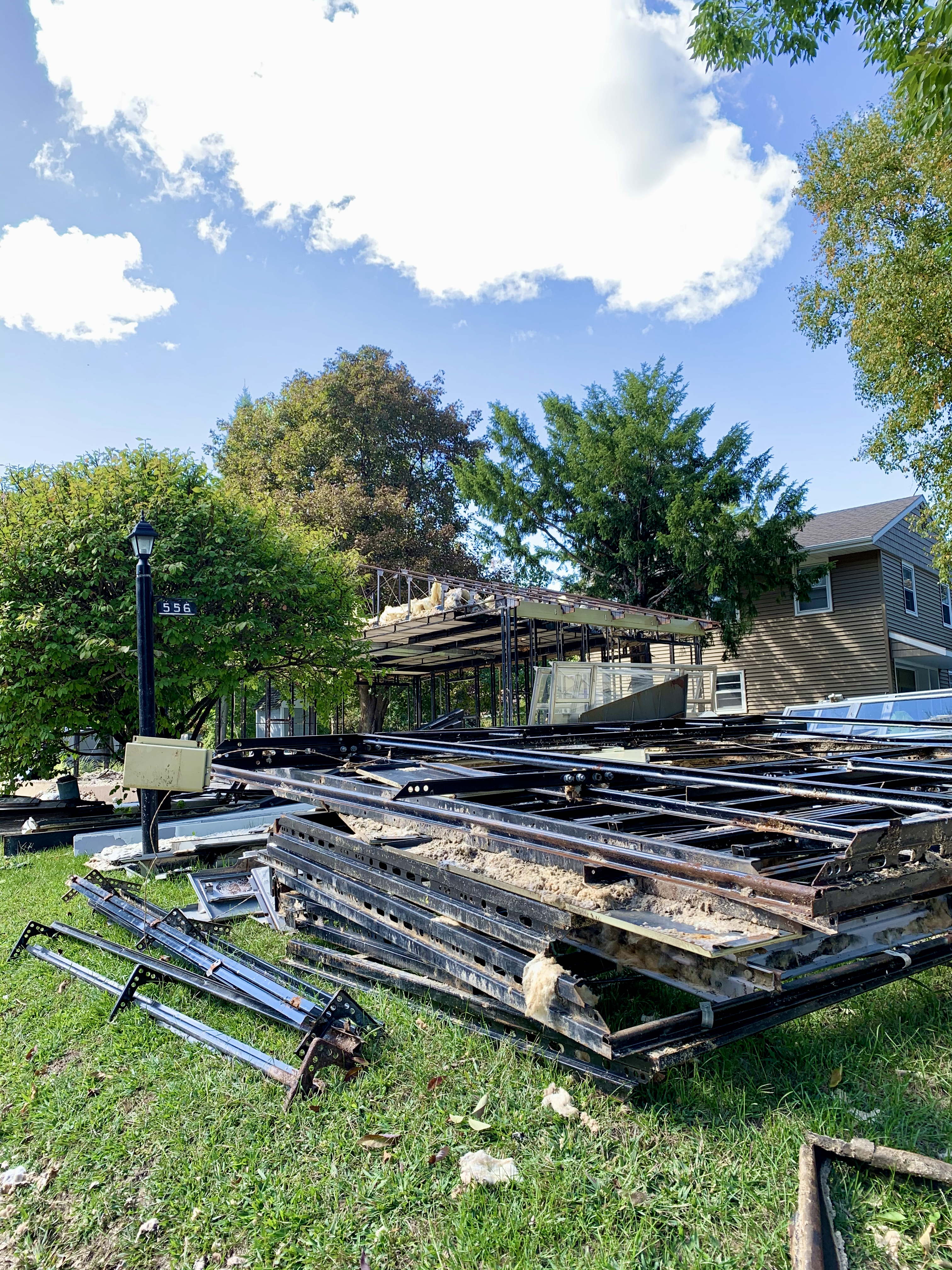 Piles of steel girders, panels, windows in front of a a skeletal roof