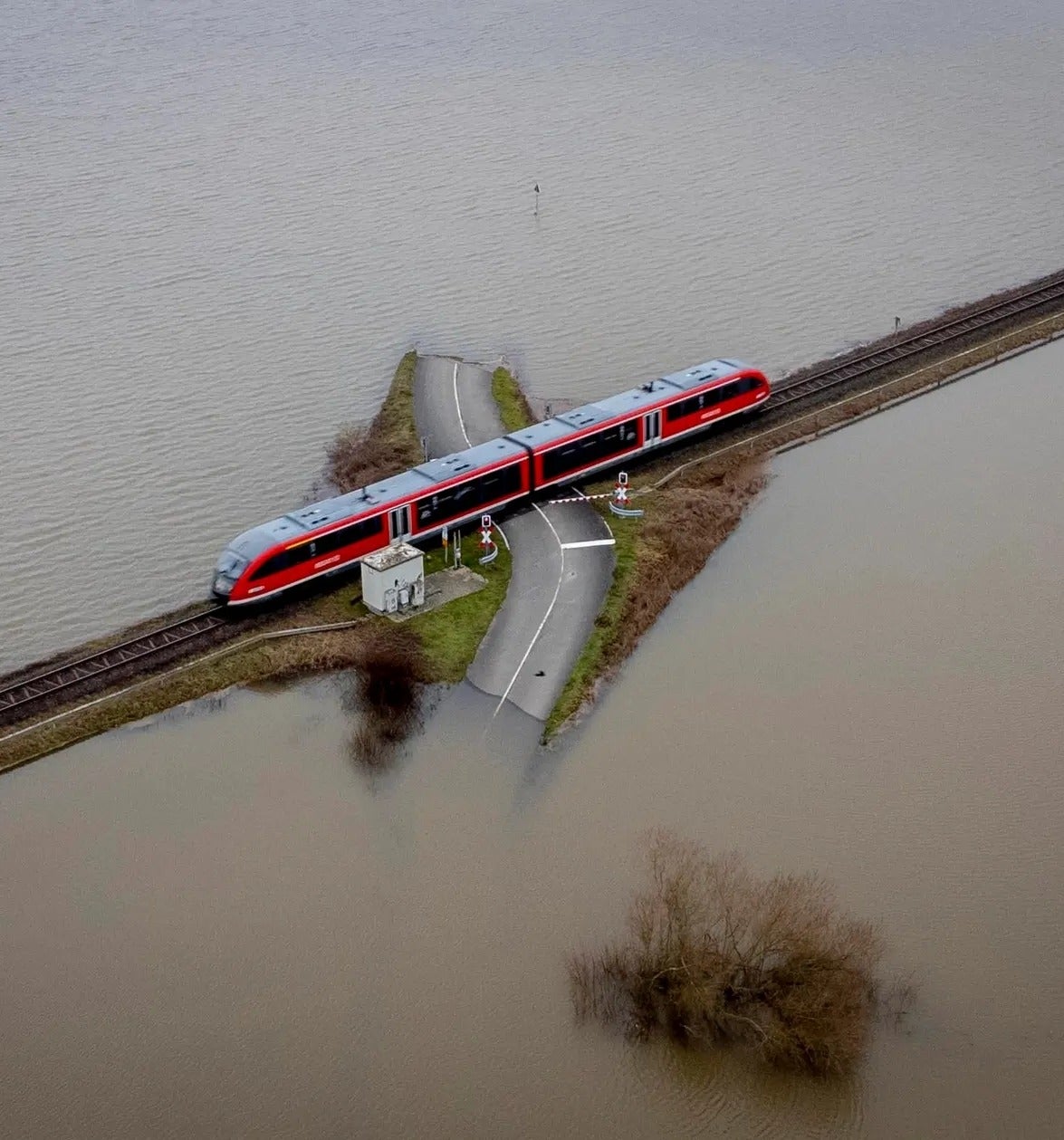 a-regional-train-passes-a-railroad-crossing-between-flooded-fields