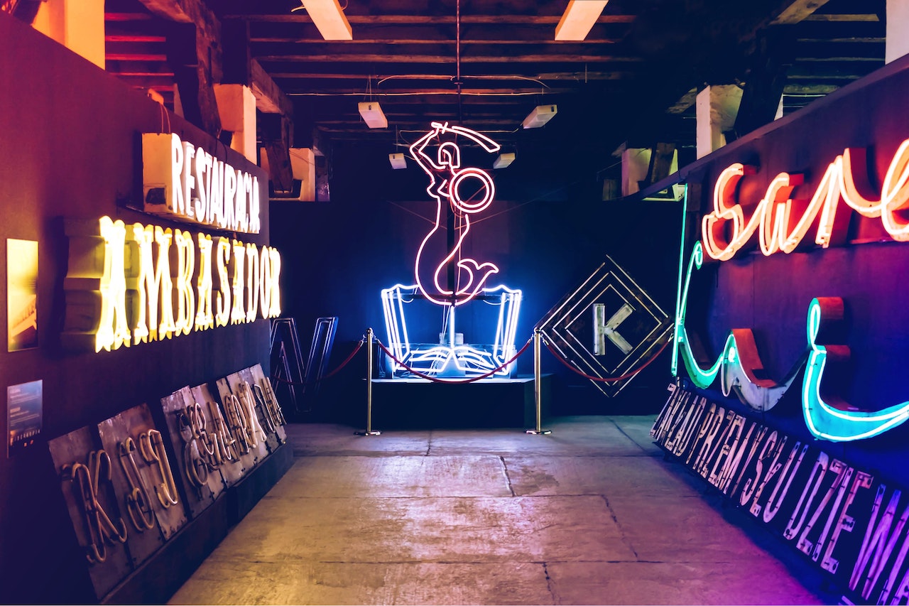 Neon signs inside a hall including a mermaid with a sword and shield.